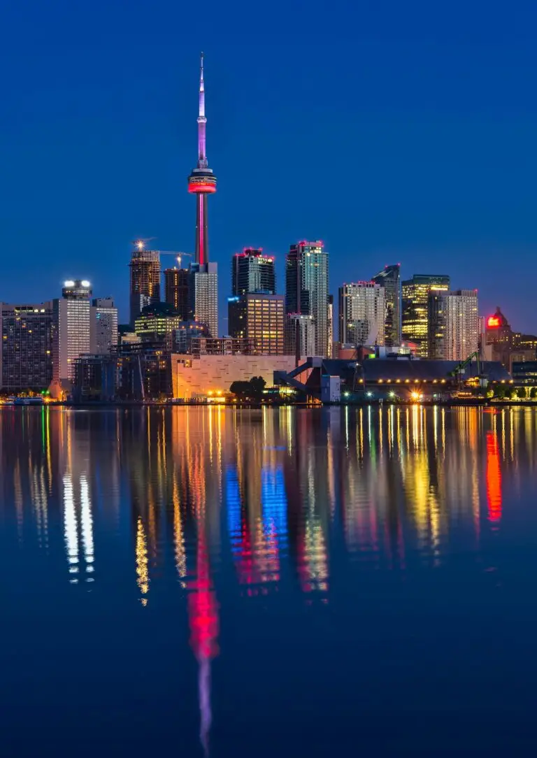 Beautiful nighttime view of Toronto skyline and CN Tower reflecting on calm water.